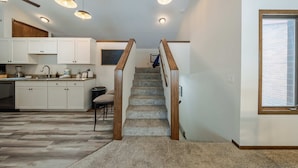 Una cocina moderna con armarios blancos, una escalera de madera y un tragaluz.