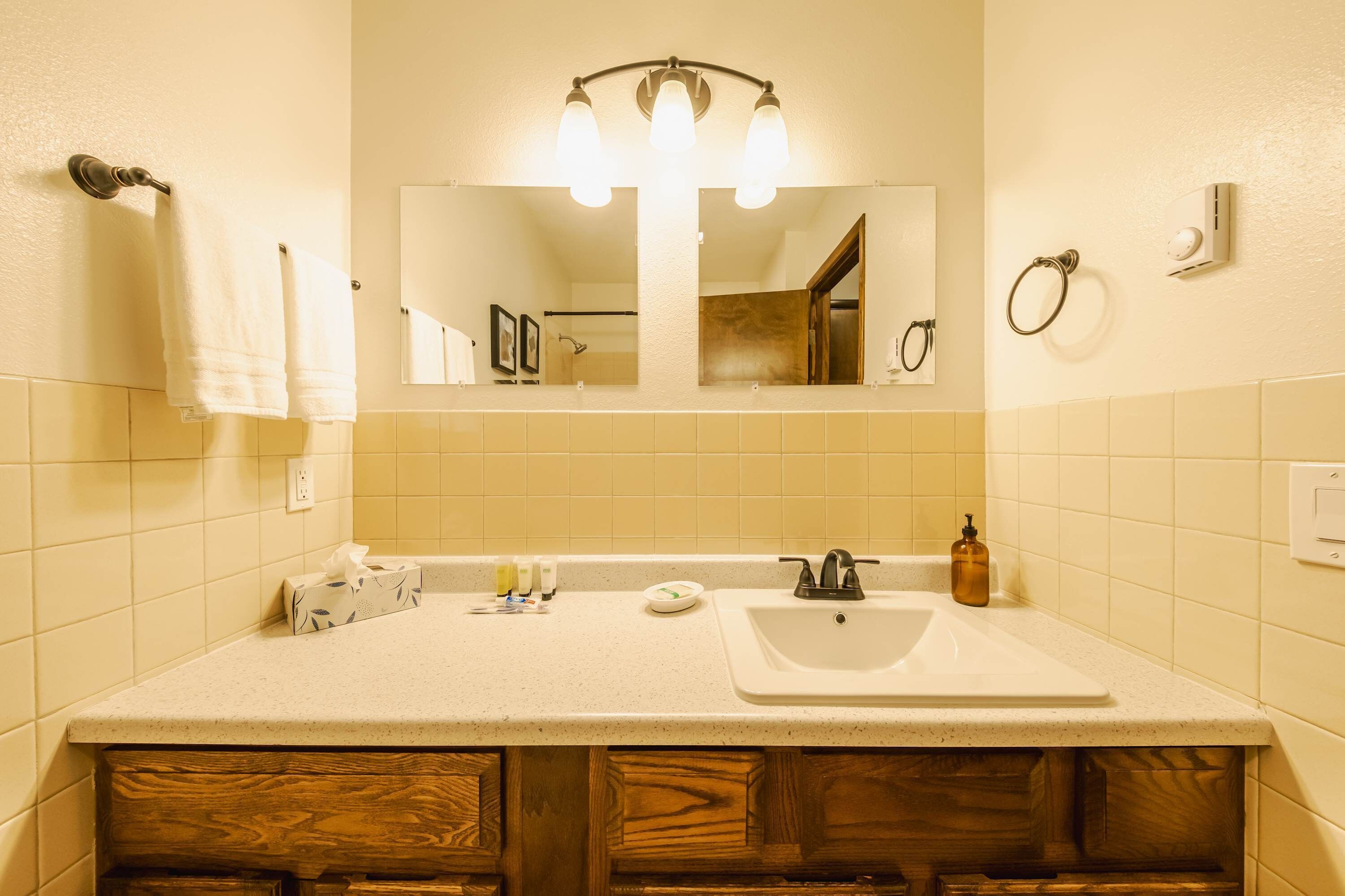 A bathroom with a sink, mirror, towel rack, and wooden cabinets.