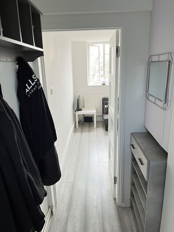 A narrow hallway with a radiator, a window, and a TV mounted on the wall.