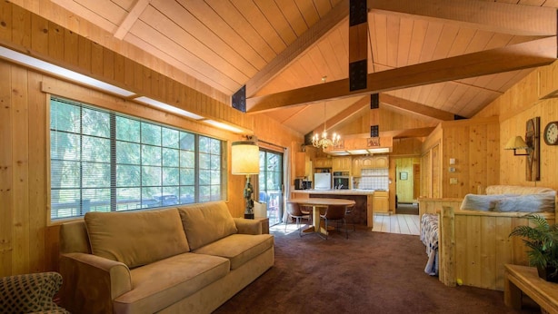 A cozy cabin interior with a wooden interior, a sofa, a dining table, and a kitchen area. - Glen Lake Cabin in the Woods (Eureka)