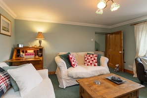 A cozy living room with a sofa, a coffee table, and a lamp.