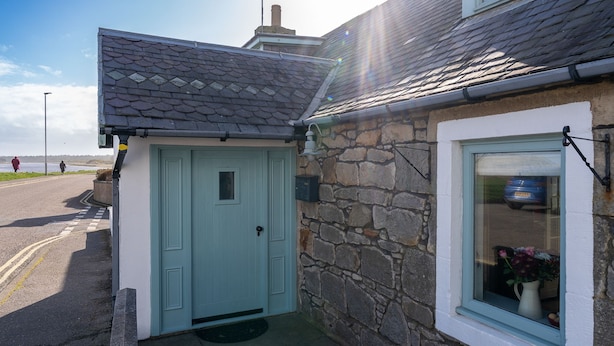 Une maison en pierre avec une porte bleu clair et une fenêtre dotée d’un cadre blanc.