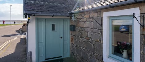 A stone house with a light blue door and a window with a white frame.
