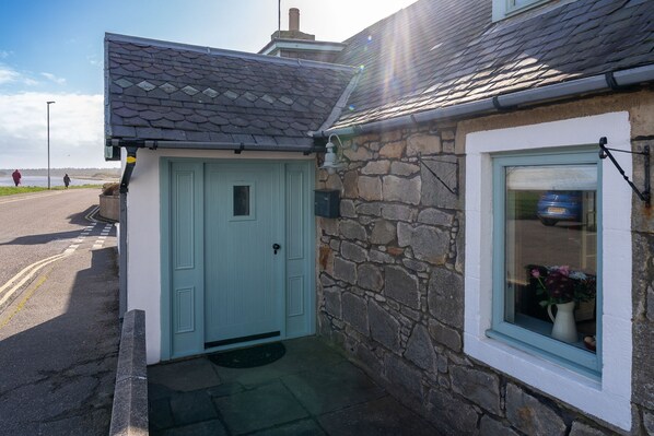 A stone house with a light blue door and a window with a white frame.