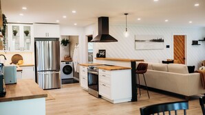 A modern kitchen with white cabinetry, stainless steel appliances, and a wooden island. - Beautiful, modern, cottage with hot tub and more (Renfrew)