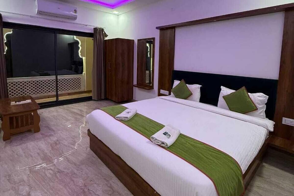 A hotel room with a large bed, a ceiling fan, and a view through the glass door.