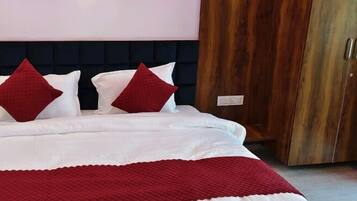 A bed with white bedding and red pillows, a dark headboard, and wooden wardrobe doors.