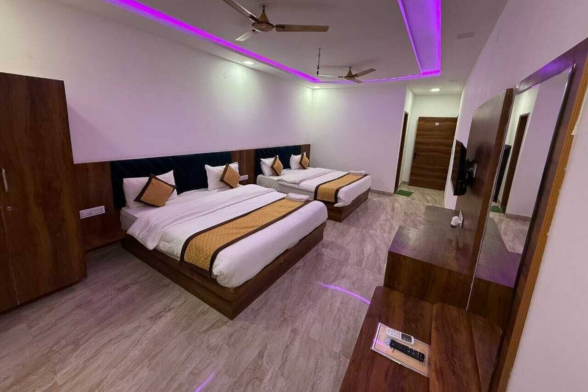 A hotel room with two beds, wooden headboards, a wardrobe, a mirror, and ceiling fans.