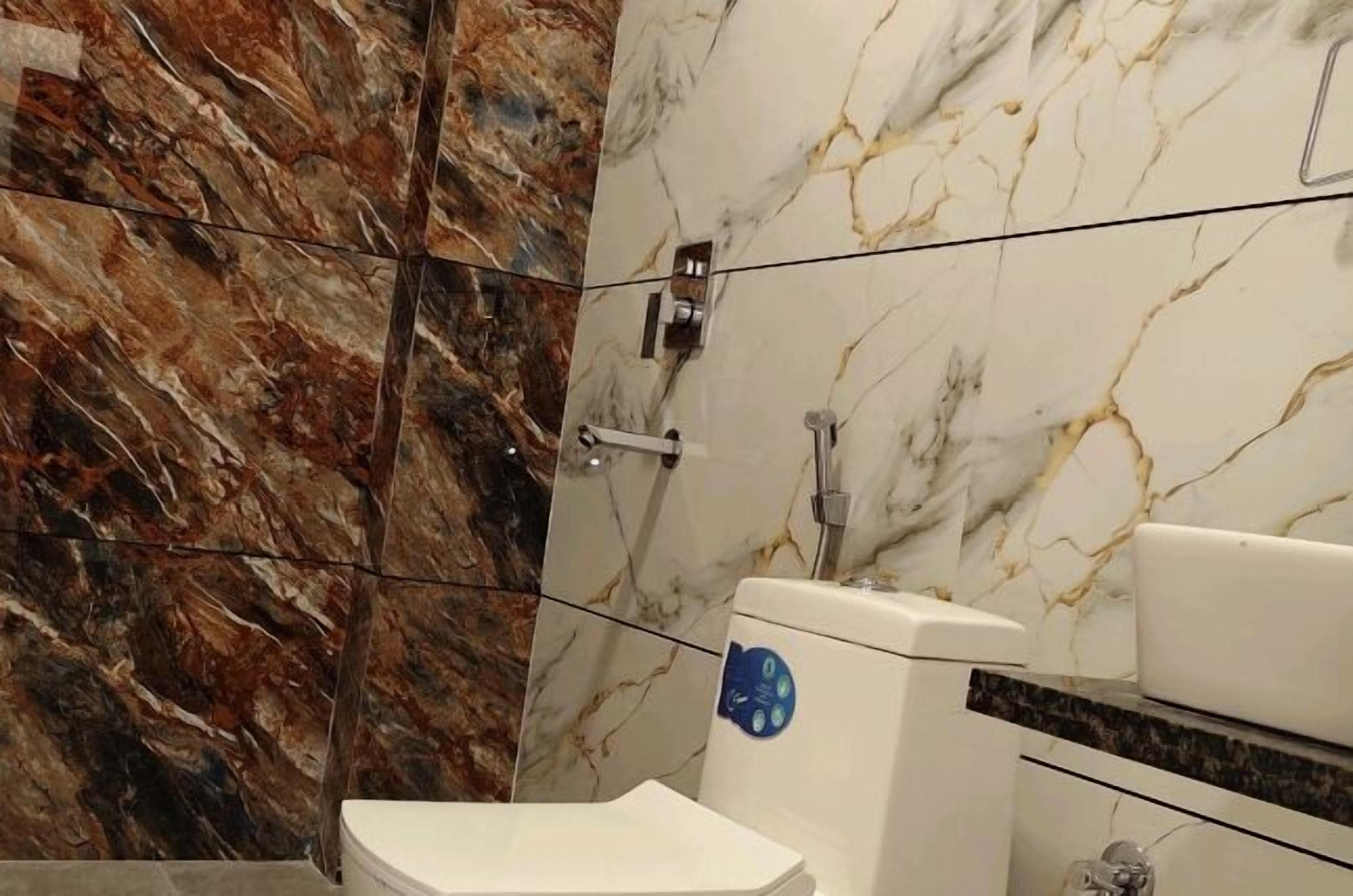 A bathroom with a marble vanity, a toilet, and a shower area with a marble wall.