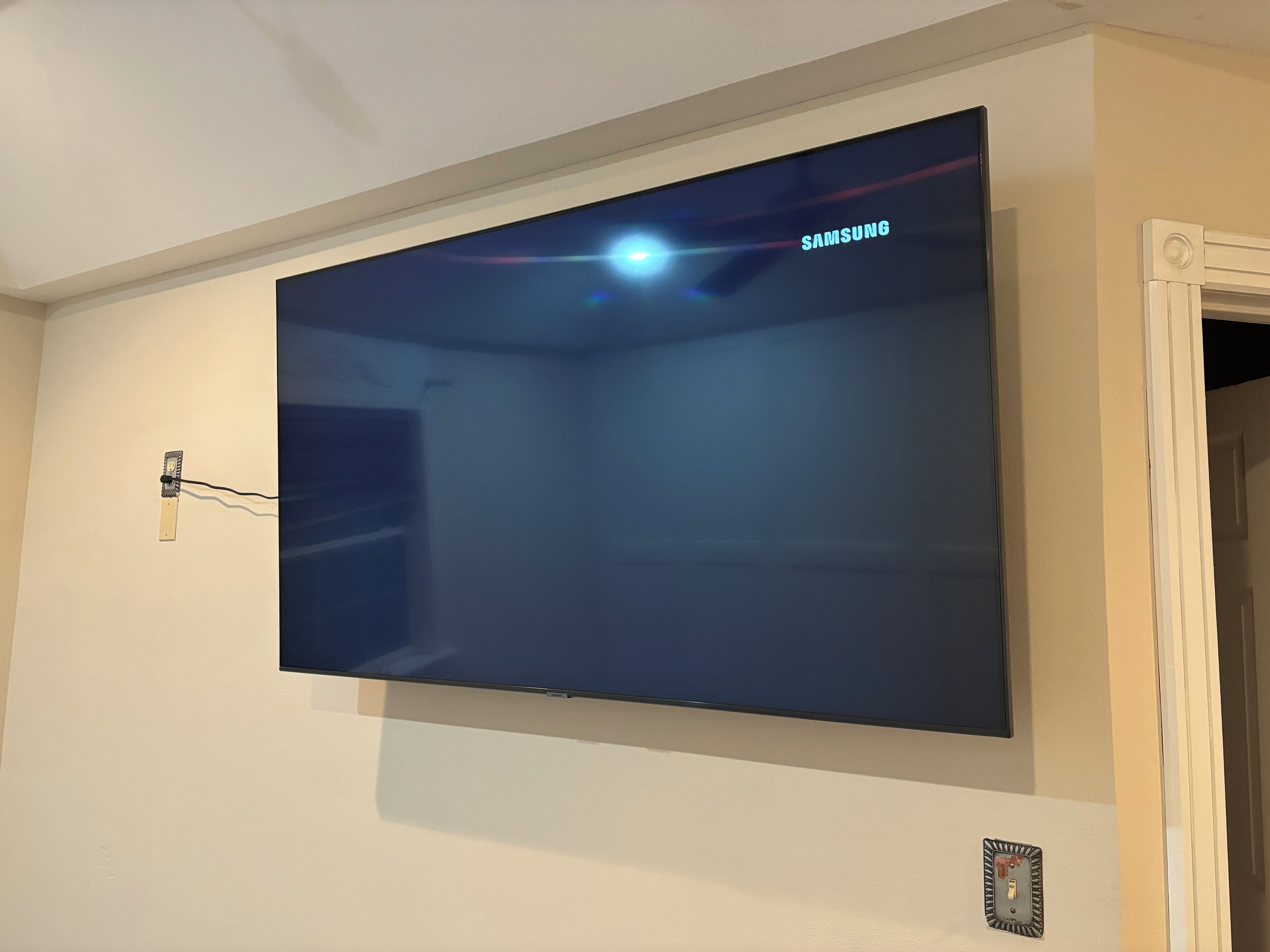 Televisão de tela plana montada na parede, com o logotipo da Samsung visível.