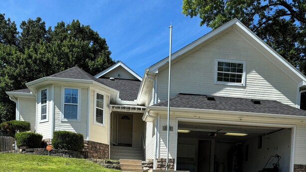 A two-story house with a front porch, a garage, and a well-maintained lawn.