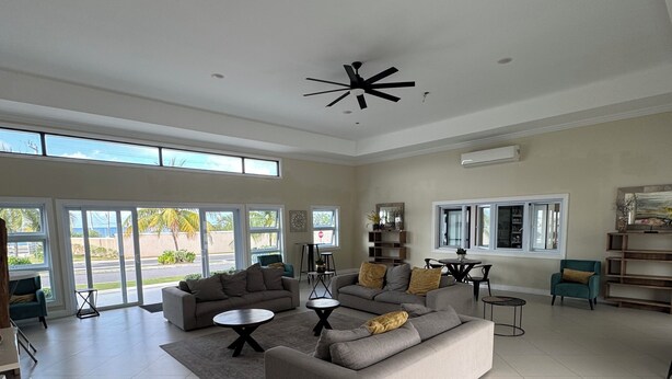 A spacious living room with a large sofa, a teal armchair, and a ceiling fan.