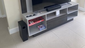 A modern entertainment unit with a flat-screen TV, a remote control, and a speaker.