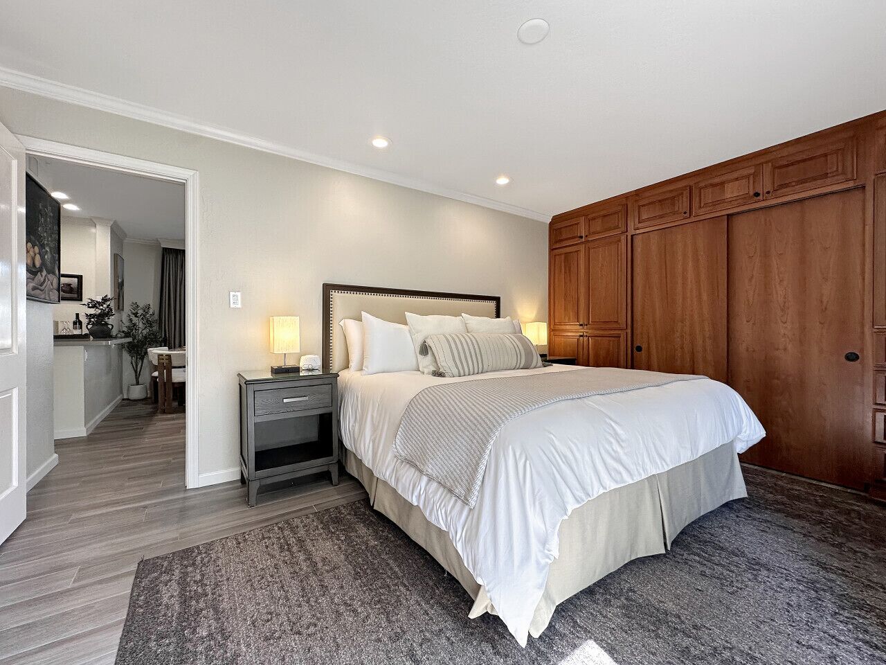 Un dormitorio con una cama grande, un armario de madera y una mesita de noche con lámpara.