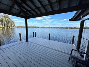 Une terrasse en bois surmontée d’un toit en métal, offrant une vue sur un lac paisible.