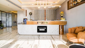 A reception area with a marble counter, a reception desk, a clock, and a framed artwork on the wall.