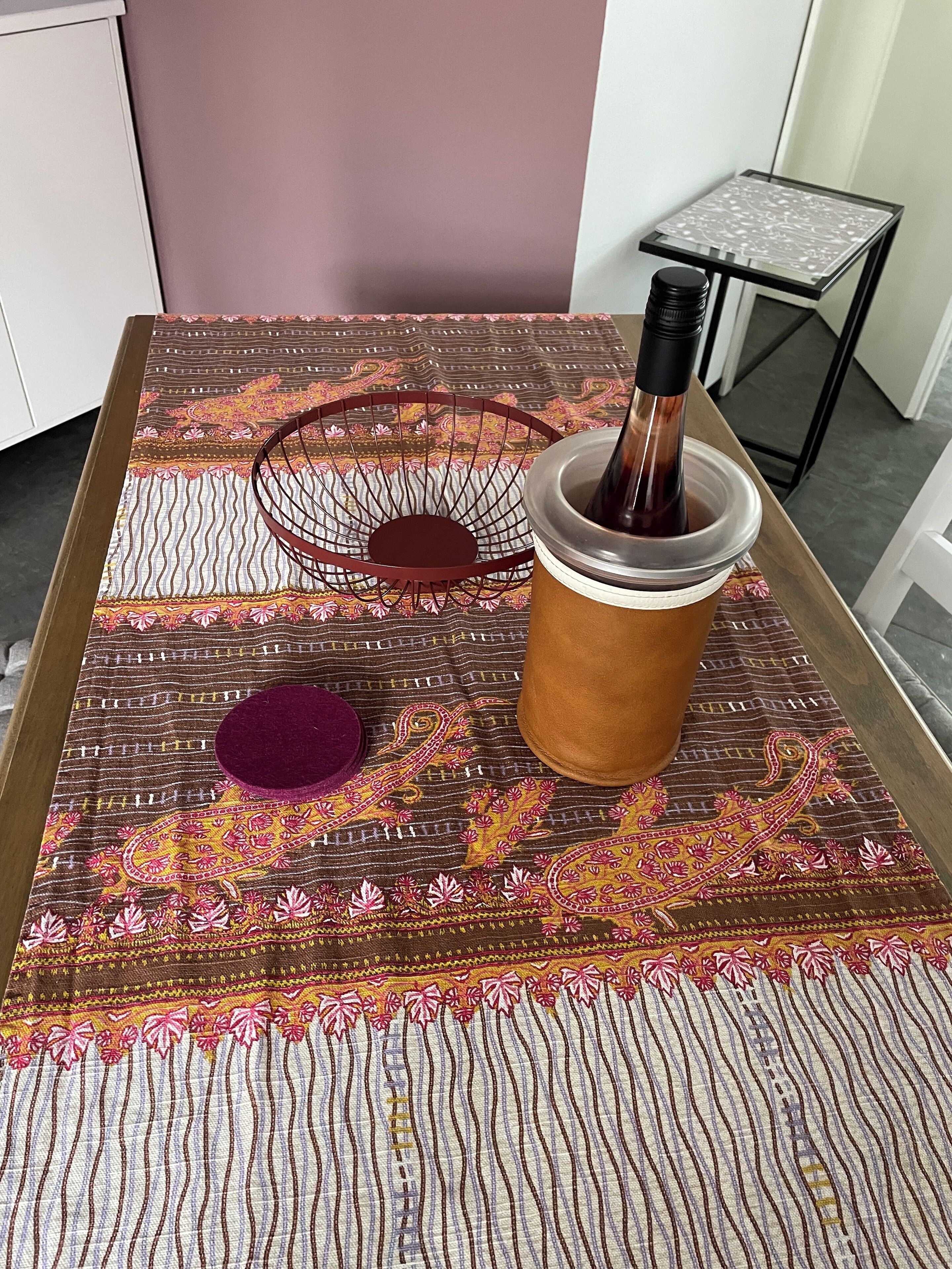 Une table recouverte d’une nappe à motifs, avec une bougie et une tasse.