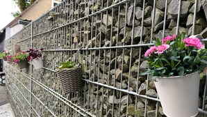 Ein Metallzaun mit Topfpflanzen und einer Steinmauer.