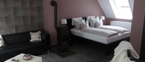 Een slaapkamer met een bed, nachtkastje, lamp, kast, raam en een bank.