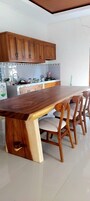 Uma mesa de jantar de madeira com cadeiras, uma área de cozinha com armários e um chão de azulejos.
