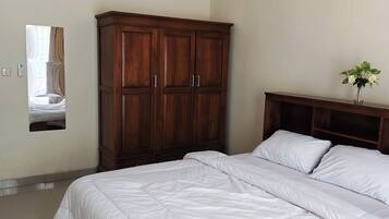 A bedroom with a large bed, wooden wardrobe, and a mirror on the wall.