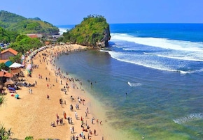 Uma praia com pessoas, um penhasco e o oceano.
