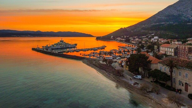 Un pueblo costero con un puerto deportivo, barcos y un gran barco atracado.