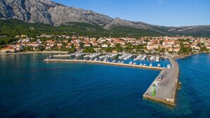 Un pueblo costero con un puerto deportivo, casas y montañas al fondo.