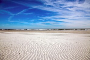 Una playa con ondulaciones de arena y un cielo azul despejado.