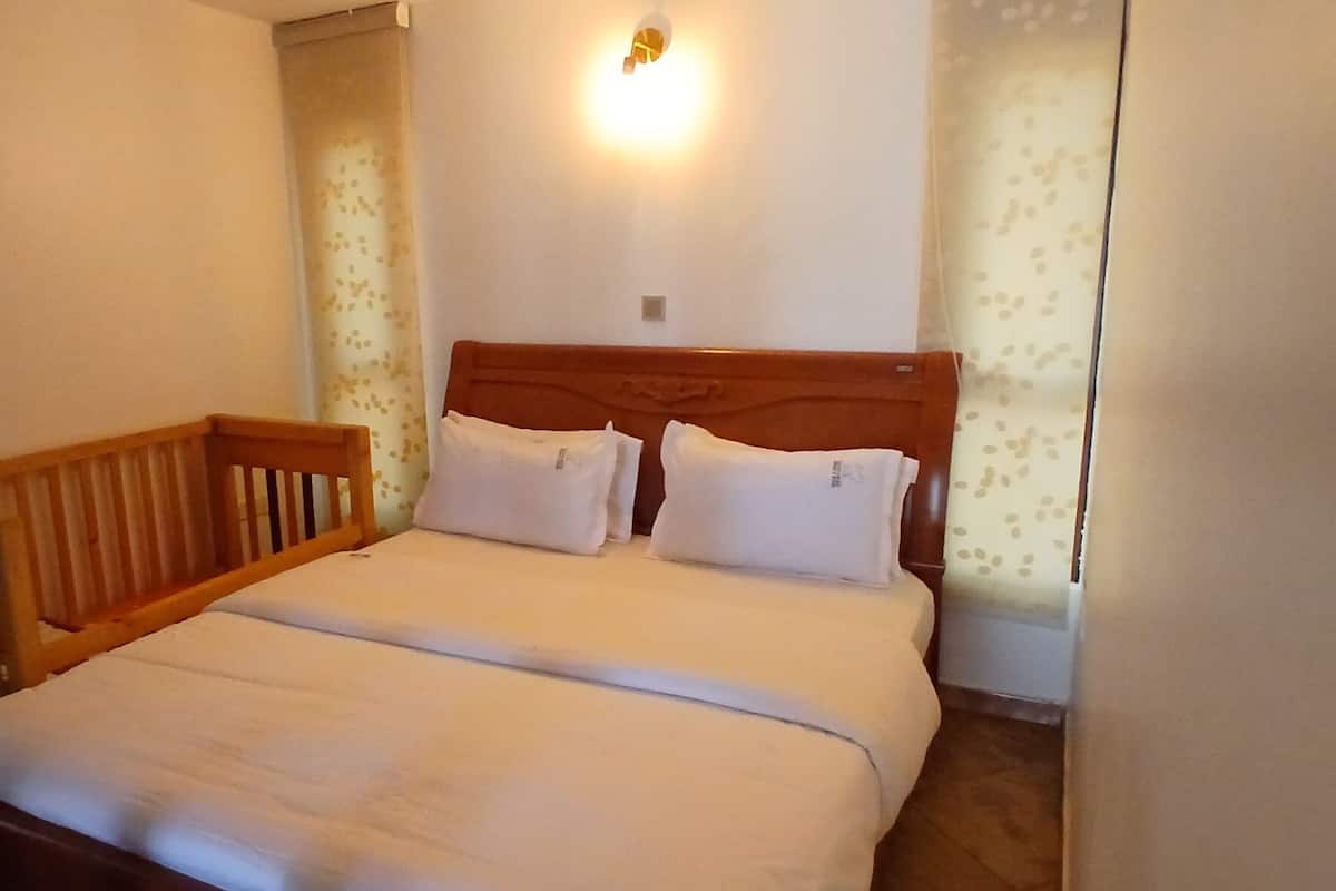A bedroom with a wooden headboard, two white pillows, and a light fixture above the bed.
