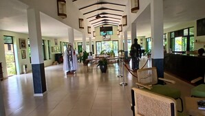 Eine großzügige Lobby mit hoher Decke, einem Empfangsbereich und einer Sitzecke mit Stühlen und einem Tisch.