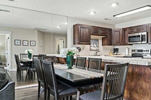 Una cocina moderna con armarios de madera oscura, un microondas de acero inoxidable y una isla grande con un lavamanos.