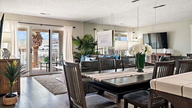 Un espace repas moderne avec une grande table, des chaises en bois foncé et une vue sur l’extérieur grâce à des portes vitrées.