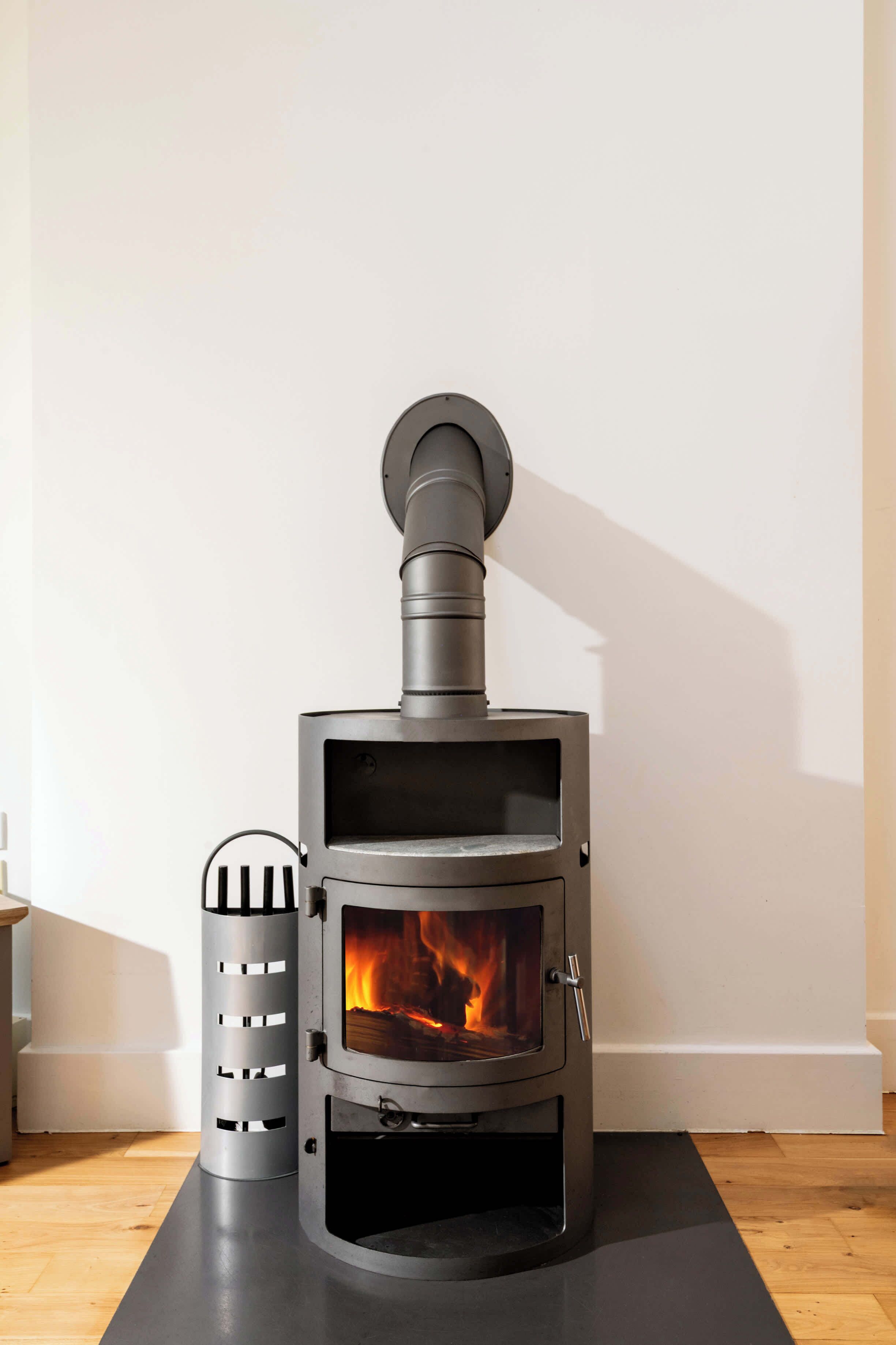 A modern wood-burning stove with a chimney, a metal vent, and a glass door.