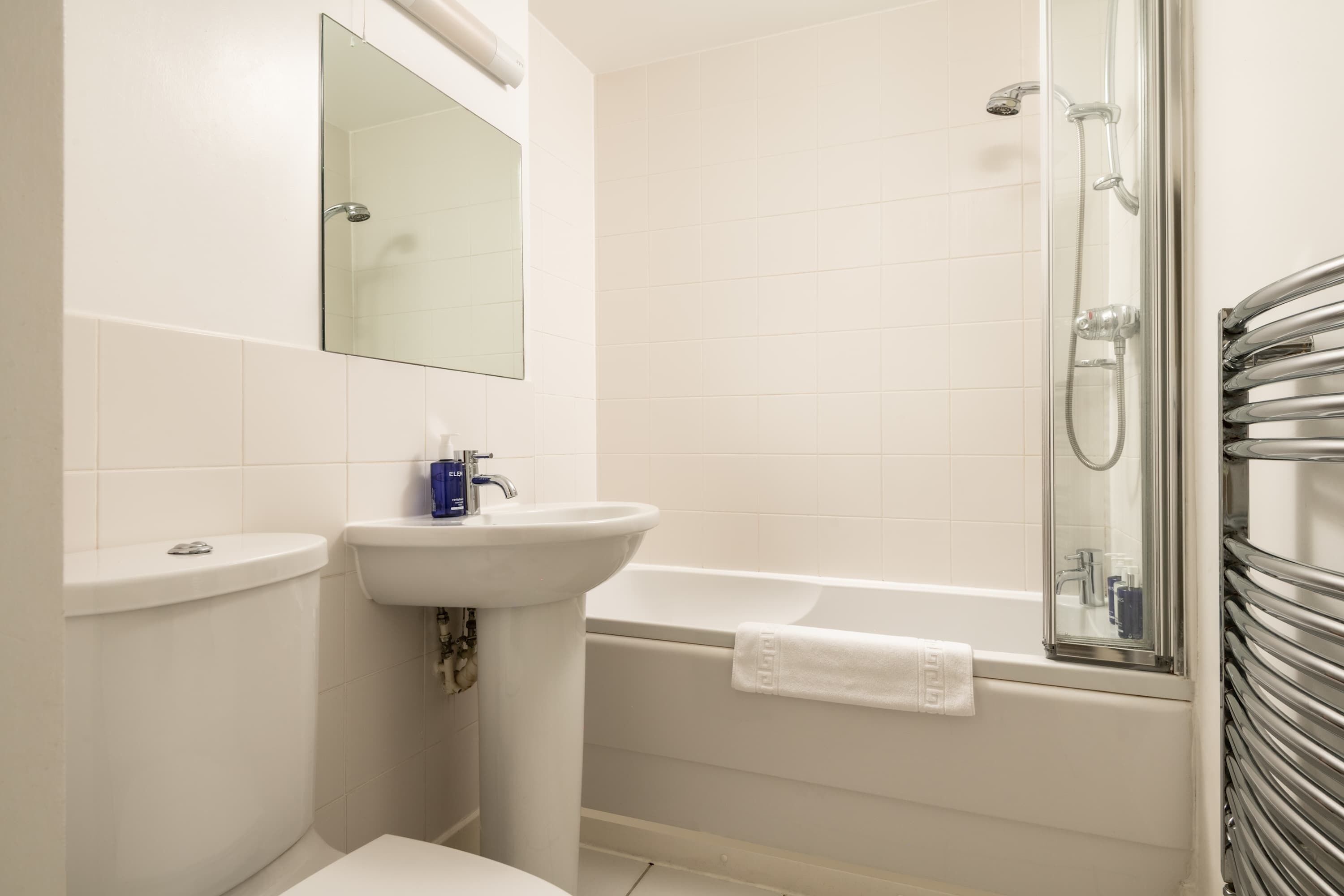 A bathroom with a toilet, sink, mirror, shower, and bathtub.