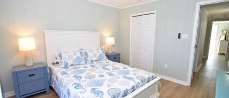 A bedroom with a bed, nightstands, a ceiling fan, and a door.