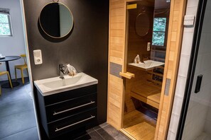A modern bathroom with a black vanity, a round mirror, and a wooden shower enclosure. - Romantic Loft w/ Garden Terrace (Ermelo)