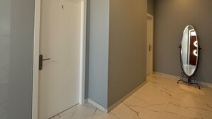 Un couloir avec une porte blanche, un miroir et un sol en marbre.