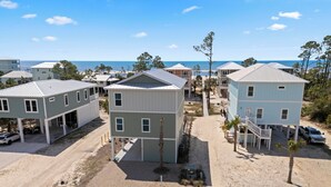 A coastal residential area with multiple two-story houses, a sandy beach, and a clear view of the ocean.