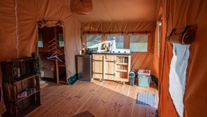 Une tente équipée d’un coin cuisine, d’un plancher en bois et d’un luminaire suspendu.