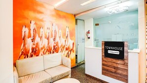 A reception area with a sofa, a reception desk, and a mural of horses. - Classic Tisya Pitampura West Enclave (New Delhi)