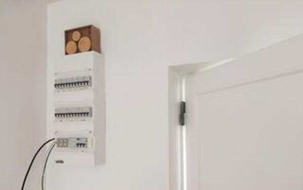 A white door with a wall-mounted electrical panel and a small wooden box with circular objects. - 5 Star Holiday Home in Liseleje (Liseleje)