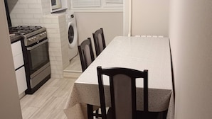 Eine kompakte Küche mit Esstisch, Stühlen, Herd, Waschmaschine und Mikrowelle.