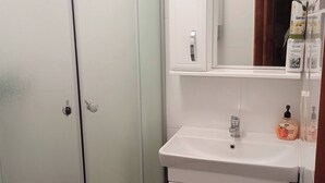 Ein Badezimmer mit Waschbecken, Spiegel und Duschkabine.