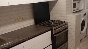 Eine Küche mit weißen Schränken, einer schwarzen Arbeitsplatte, einem Herd und einer Waschmaschine.