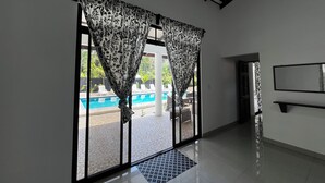 A room with large windows, a pool view, and a tiled floor. - Casa Lassie, private pool, high speed Wifi (Cahuita)