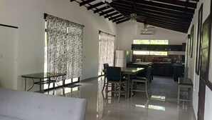 A spacious living area with a dining table and chairs, a sofa, and a kitchen in the background. - Casa Lassie, private pool, high speed Wifi (Cahuita)