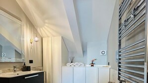 A modern bathroom with a black vanity, a large mirror, a bidet, and a towel rack.