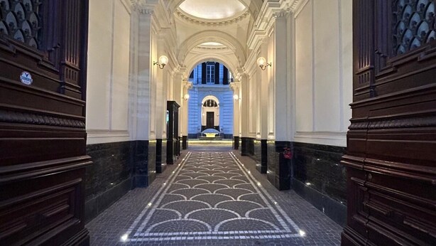 A grand hallway with a patterned floor, arched ceiling, and symmetrical wooden doors.