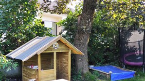 Una casita de juegos de madera con una rampa y un trampolín en un patio trasero.